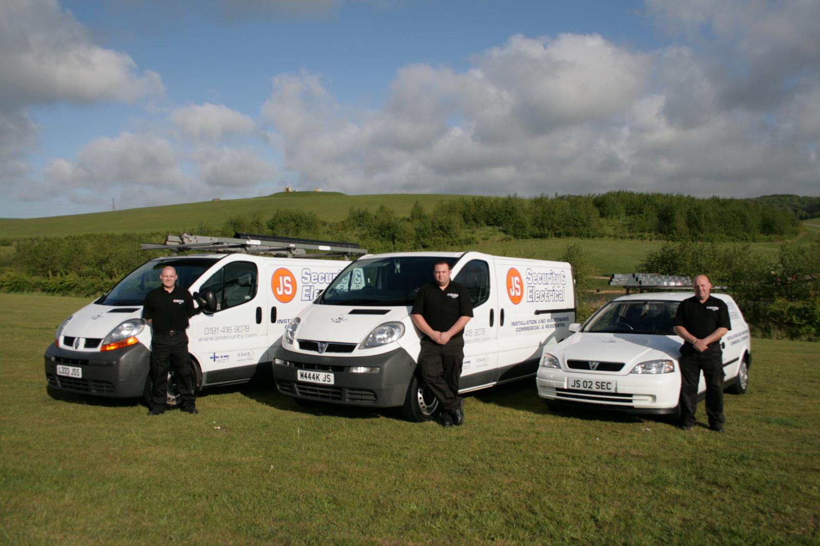 Three branded JS Security Electrical vans on a North East hillside, family business, 2000s